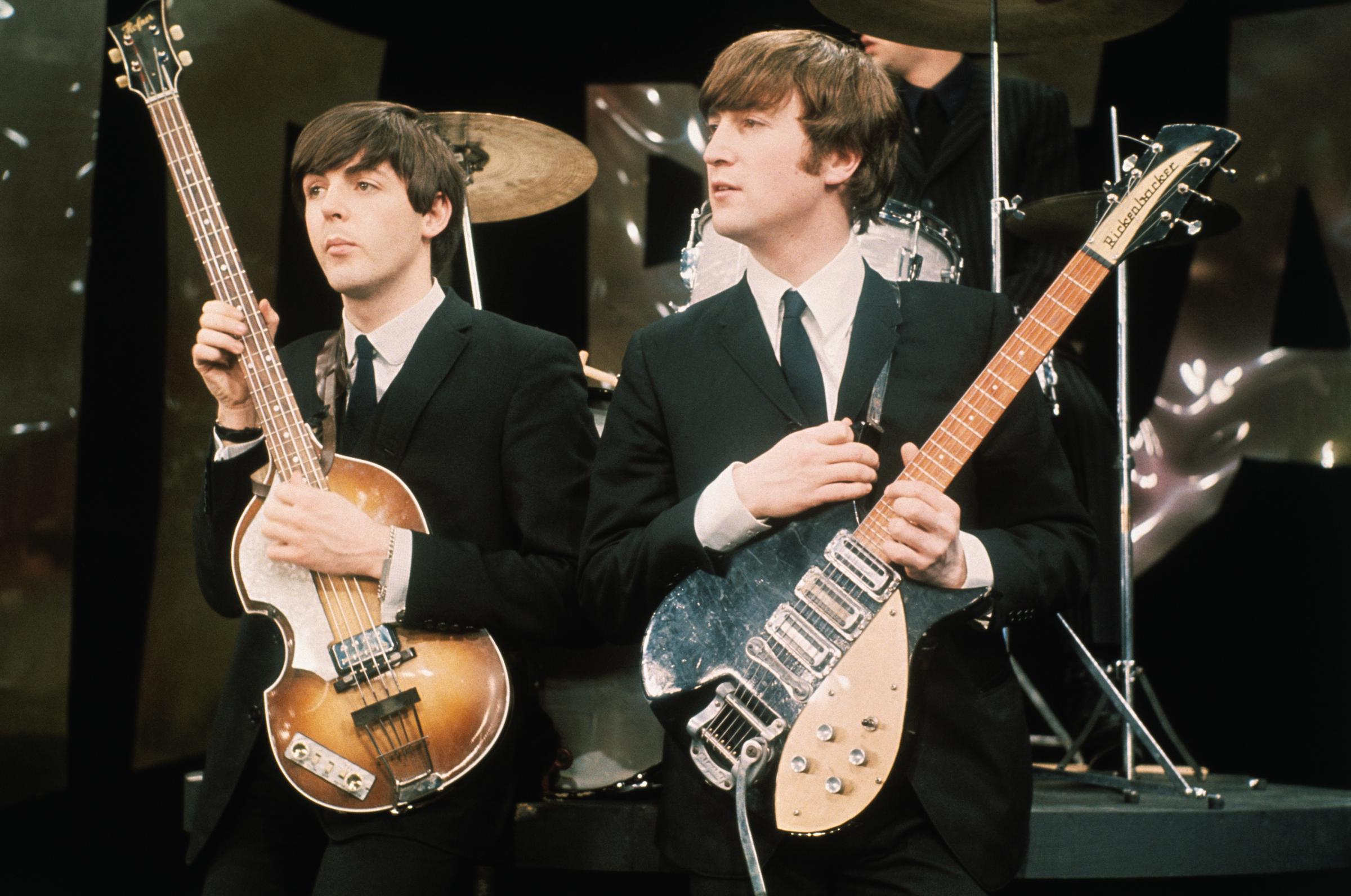 (L-R) Paul McCartney and John Lennon (1940 - 1980), of the group the Beatles, perform on the set of "The Ed Sullivan Show" at CBS's Studio 50 on February 8, 1964, in New York City. | Surce: Getty Images