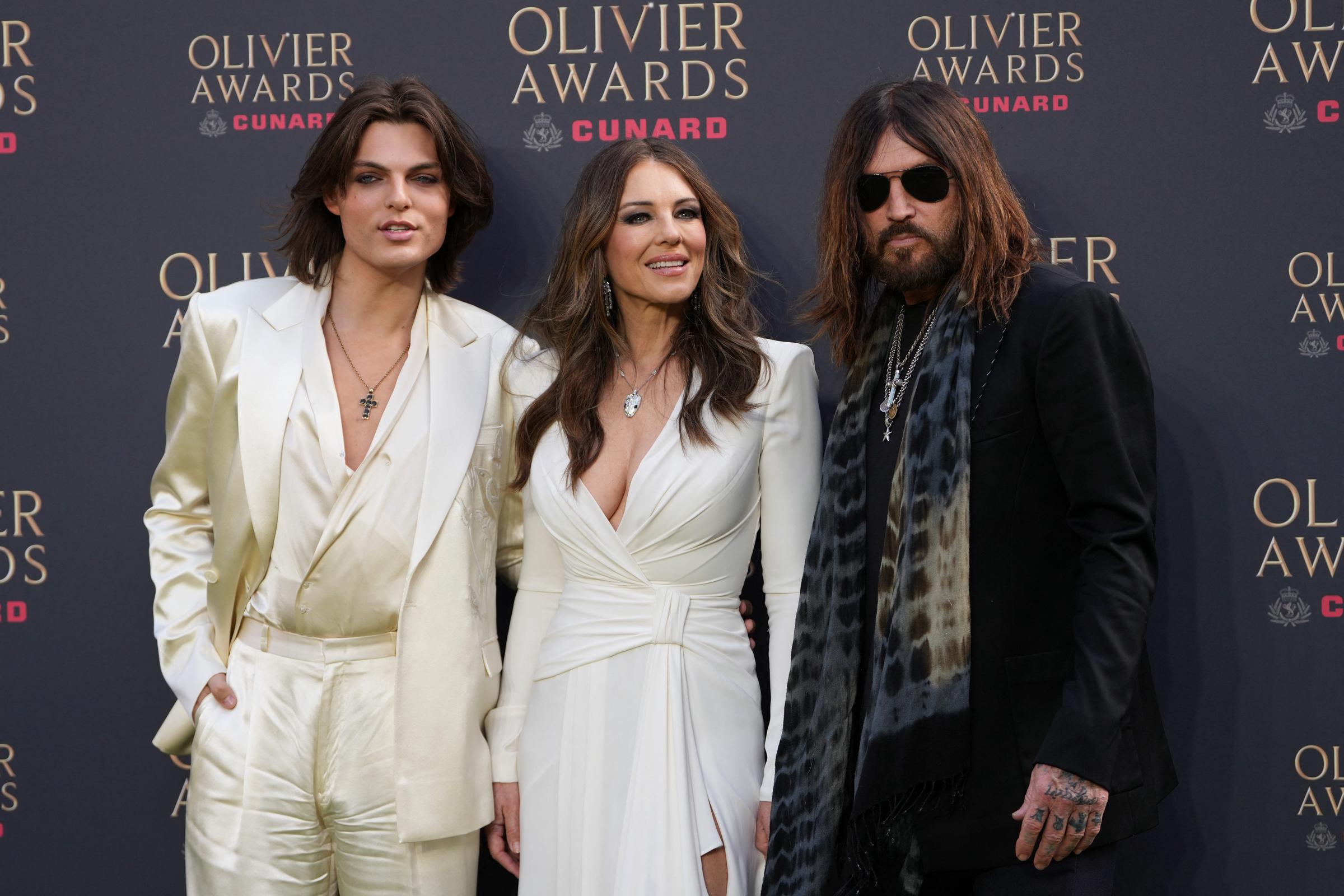 Damian Hurley, Elizabeth Hurley i Billy Ray Cyrus pozują na zielonym dywanie po przybyciu na rozdanie nagród Olivier Awards w Royal Albert Hall w centrum Londynu 12 kwietnia 2026 r. | Źródło: Getty Images